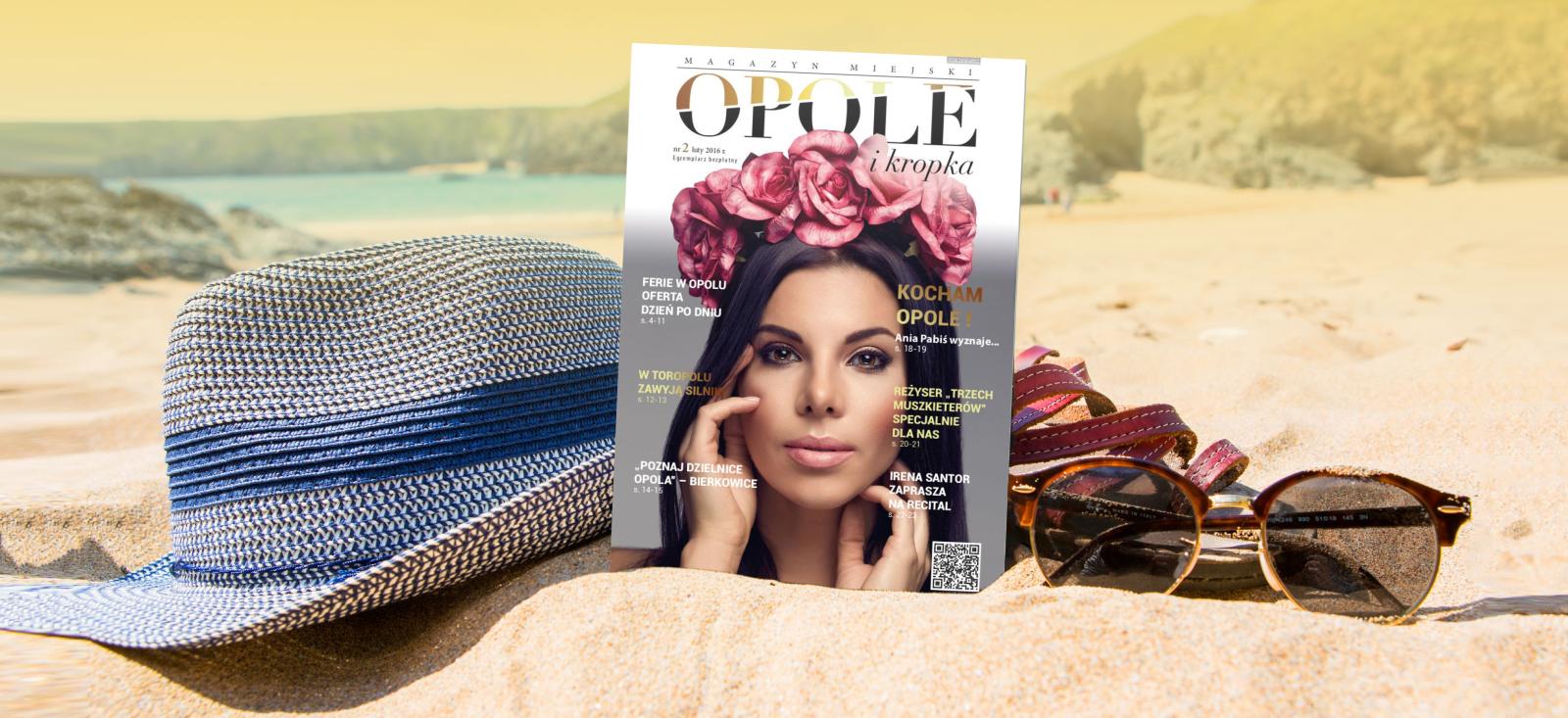 Archiwalny nymer Opole i kropka z 2026 roku na plaży. Obok kapelusza oraz okularów przeciwsłonecznych. 