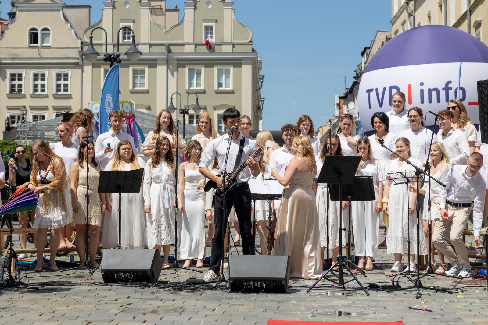chór politechniki opolskiej, chórzyści w jasnych strojach na rynku