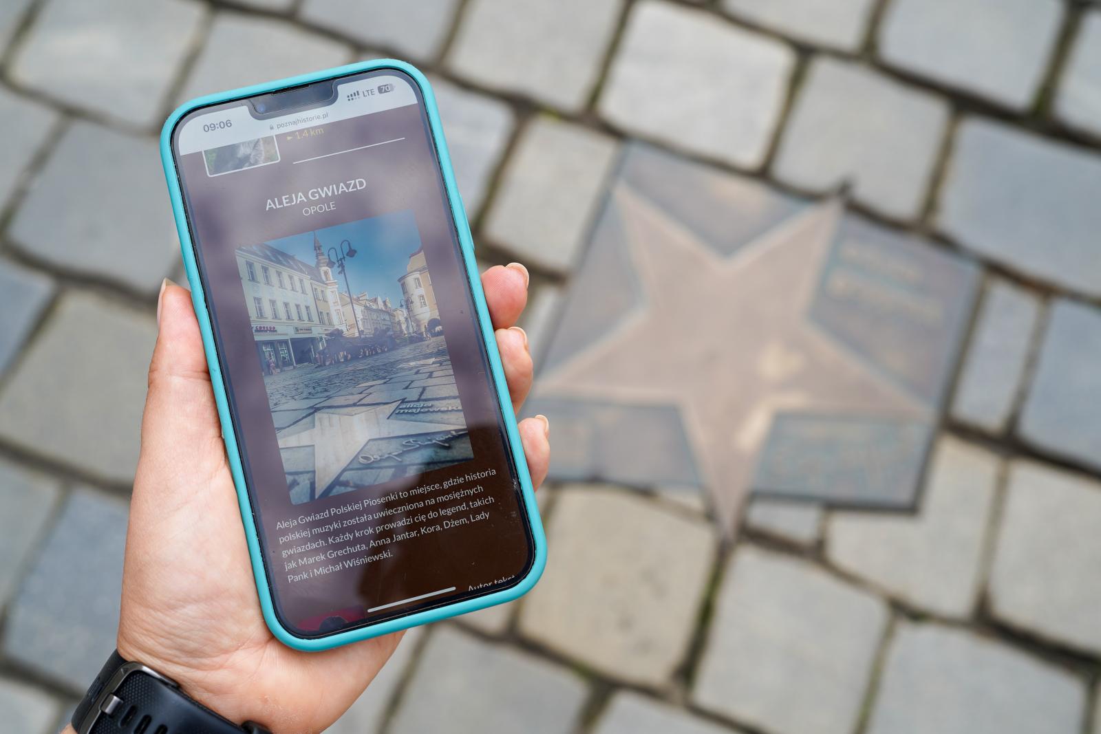 zdjęcie smartfona z odtwarzaną informacją o Alei Gwiazd, w tle gwiazda