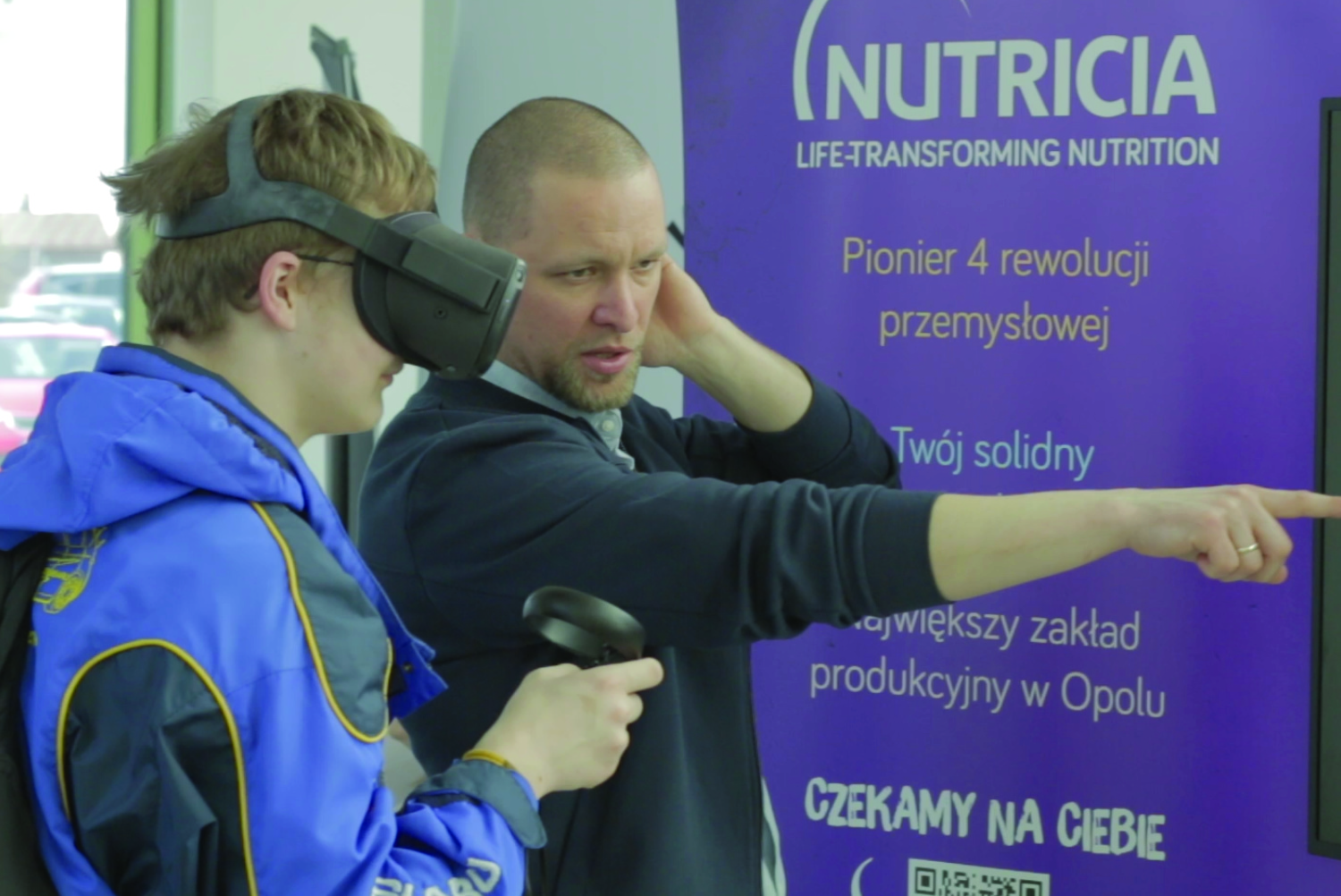 zdjęcie przedstawiające dwóch mężczyzn, jeden z googlami vr, w tle baner firmy nutricia