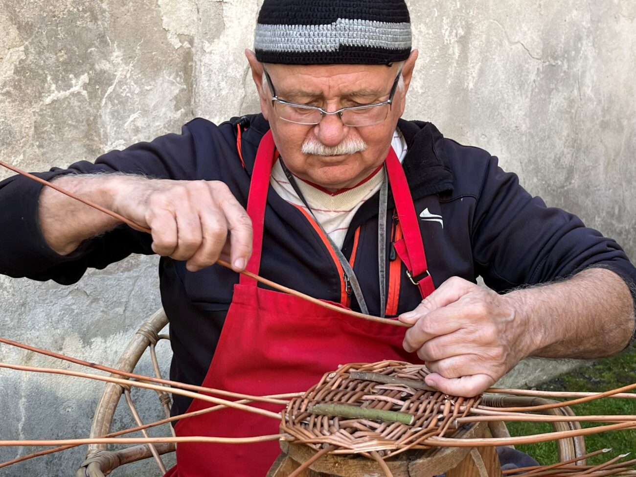mężczyzna wyplatający wiklinowy koszyk