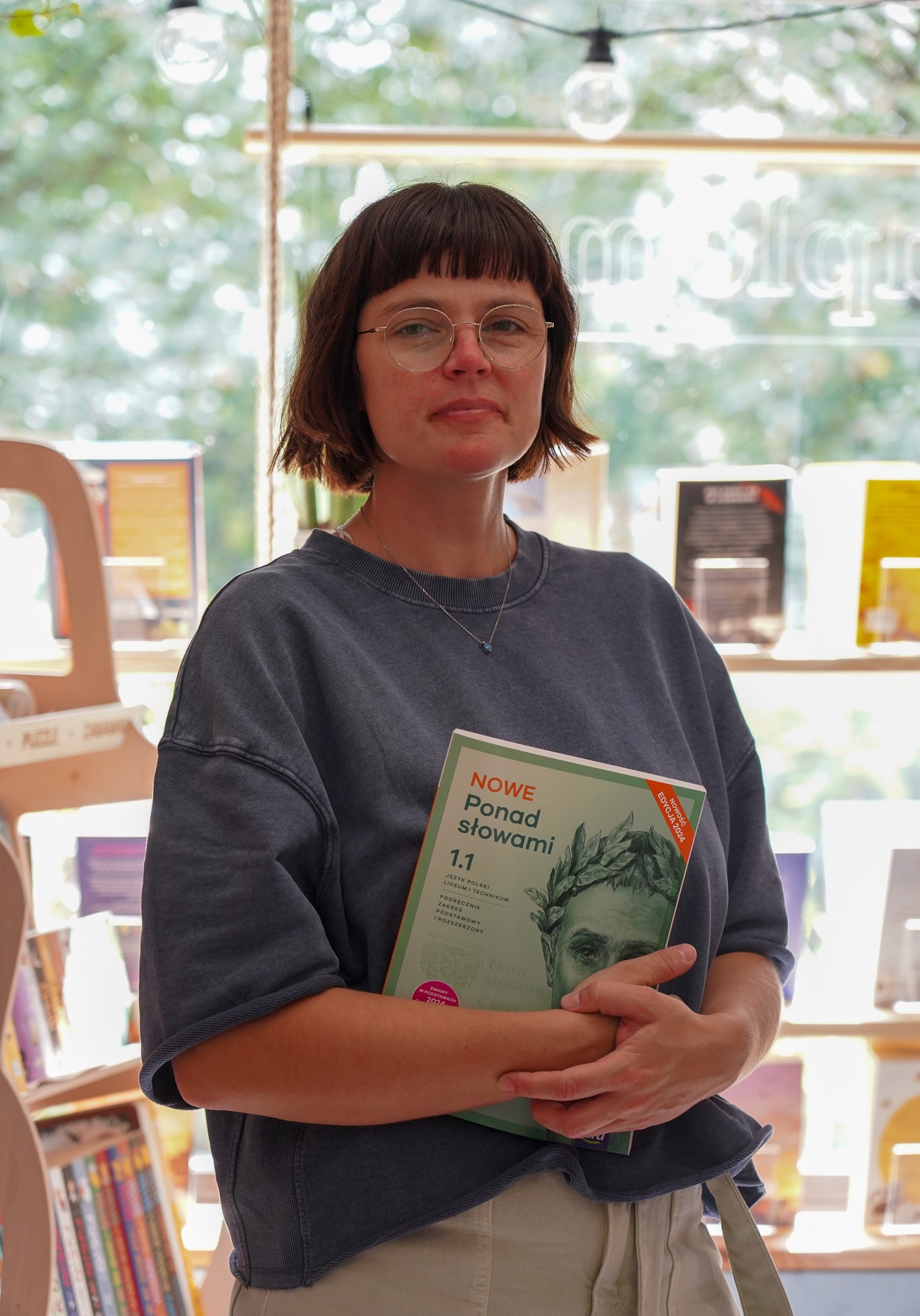 zdjęcie właścicielki księgarni, która trzyma pod ręką podręcznik