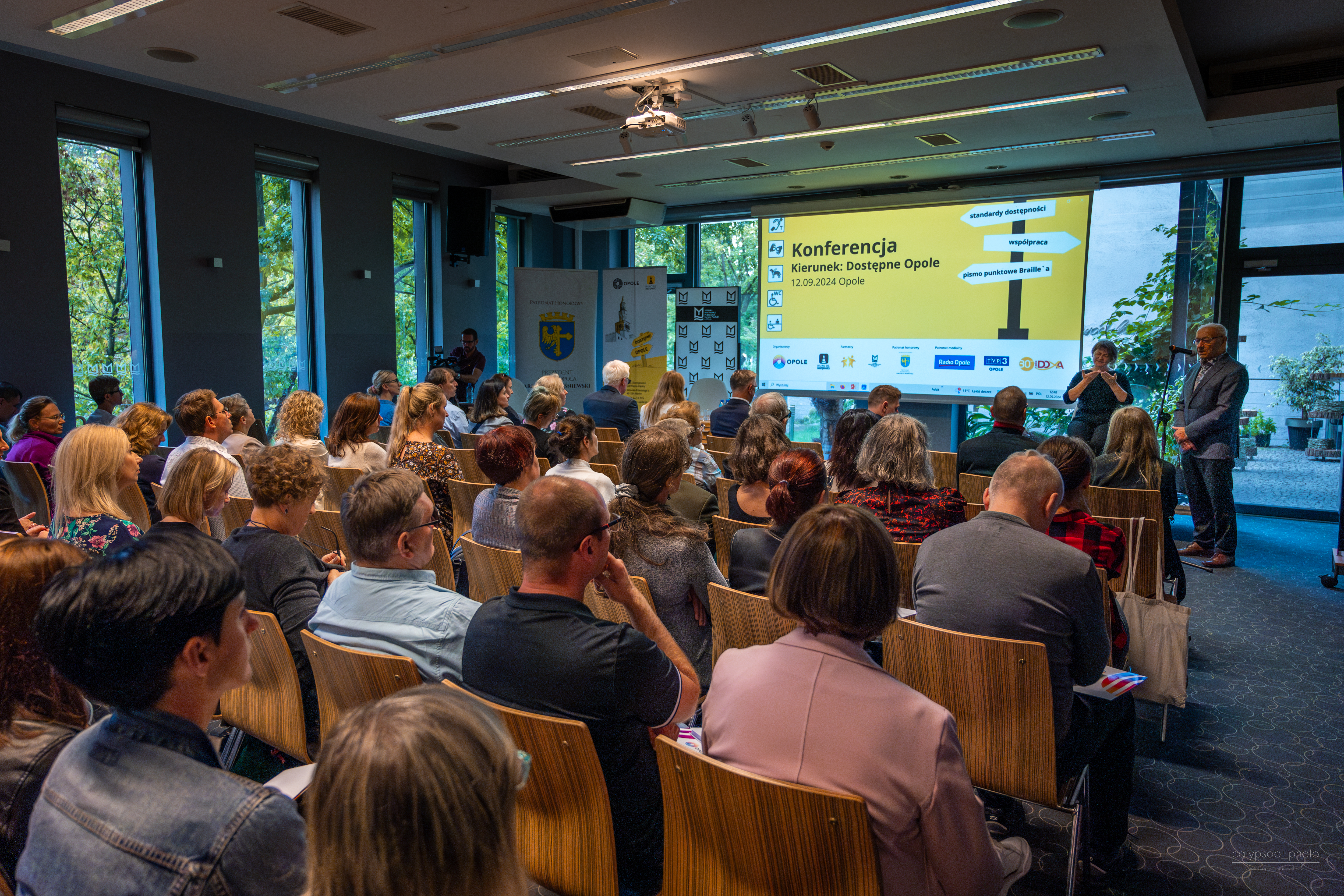 zdjęcie przedstawiające osoby siedzące przed prezentacją podczas konferencji