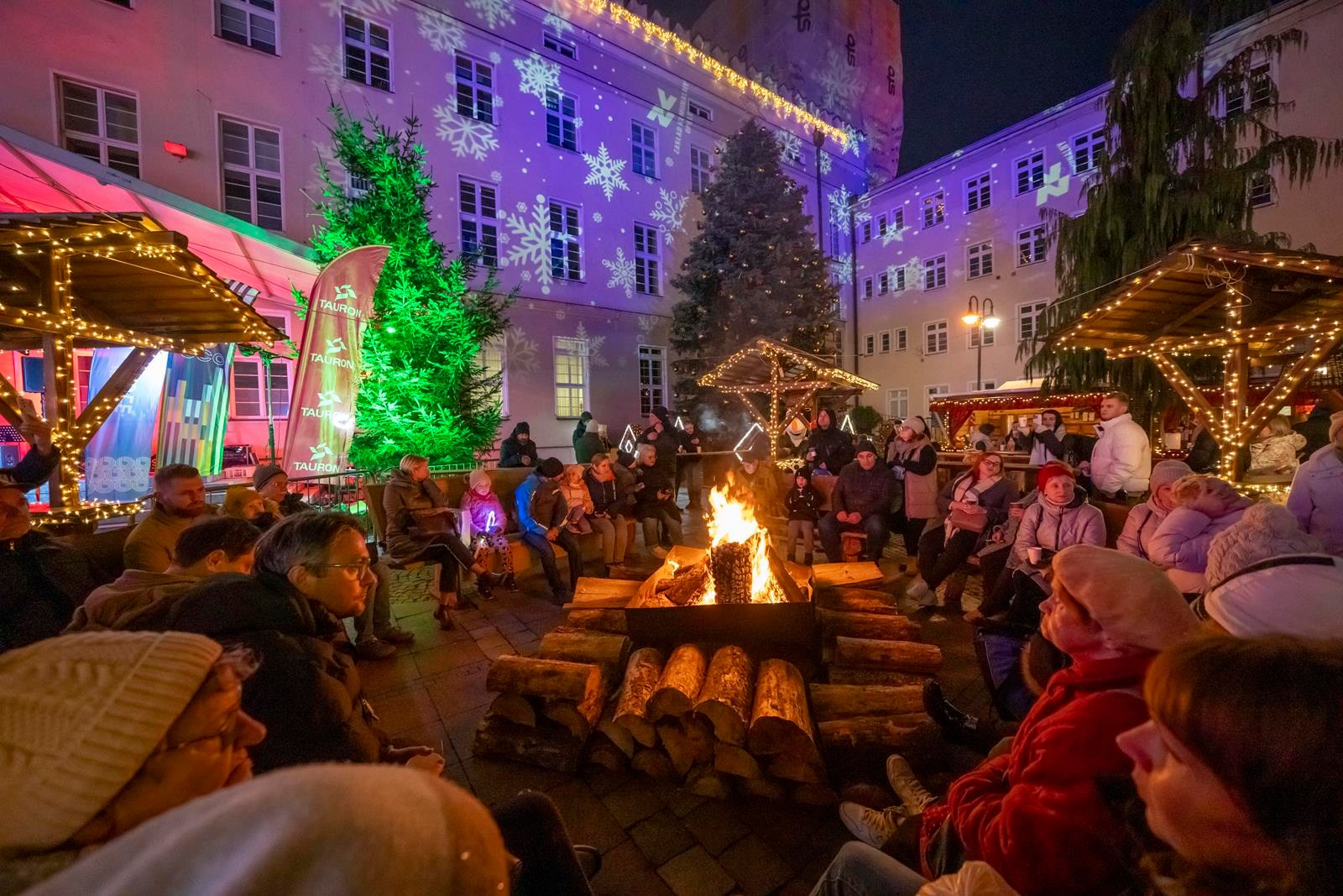 Ludzie siedzący przy ognisku na jarmarku w Opolu
