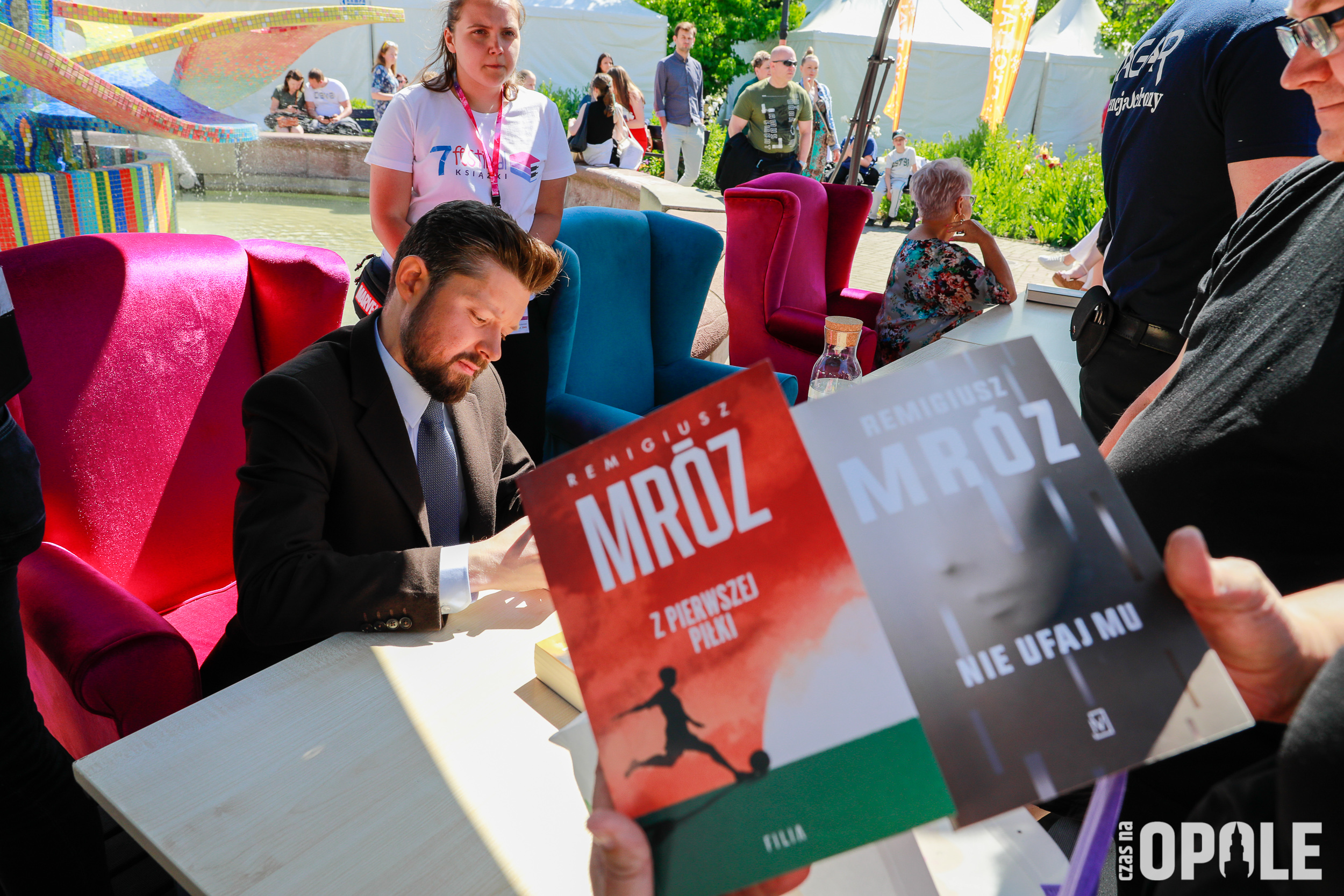 autor podpisuje autografy, mężczyzna, na ppierwszym planie okładka ksiązki