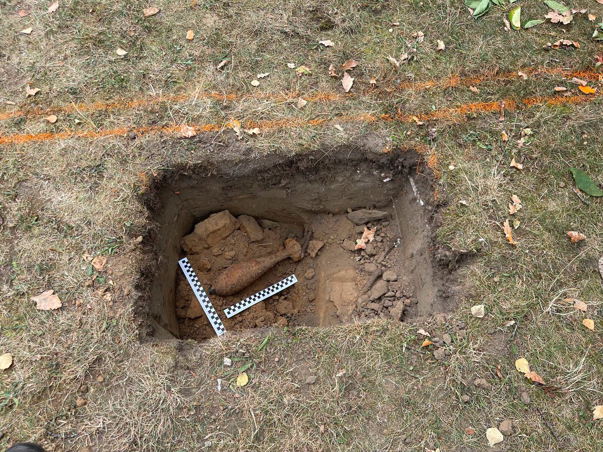 Zdjęcie przedstawiające pocisk, niewybuch w dole z ziemią