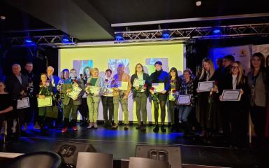 Zdjęcie grupowe uczetsników na scenie z dyplomami i różami