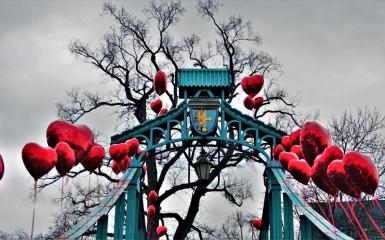 most groszowy w walentynkowej scenerii, balony czerwone w kształcie serca zawieszone na moście