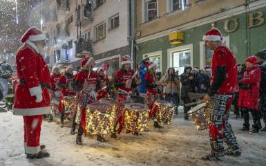 Marsz Mikołajów na ulicy Krakowskiej, gra grupa bębniarzy, pada śnieg