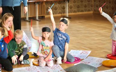  Dzieci siedza na podłodze i podnoszą rękę