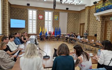 Jak opowiadać o kulturze prostym językiem? Sala opolskiego ratusza, grupa ludzi siedzących przy stole, część teoretyczna spotkania. 