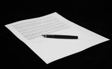 kartka papieru zapisanego do połowy z leżącym na niej piórem