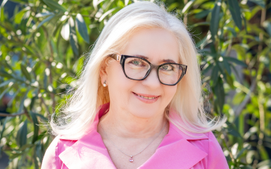 postać pani dyrektor, kobieta w okularach i różowej sukience