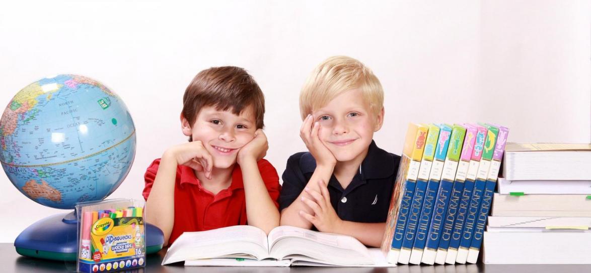 Dzieci przy ławce szkolnej z globusem