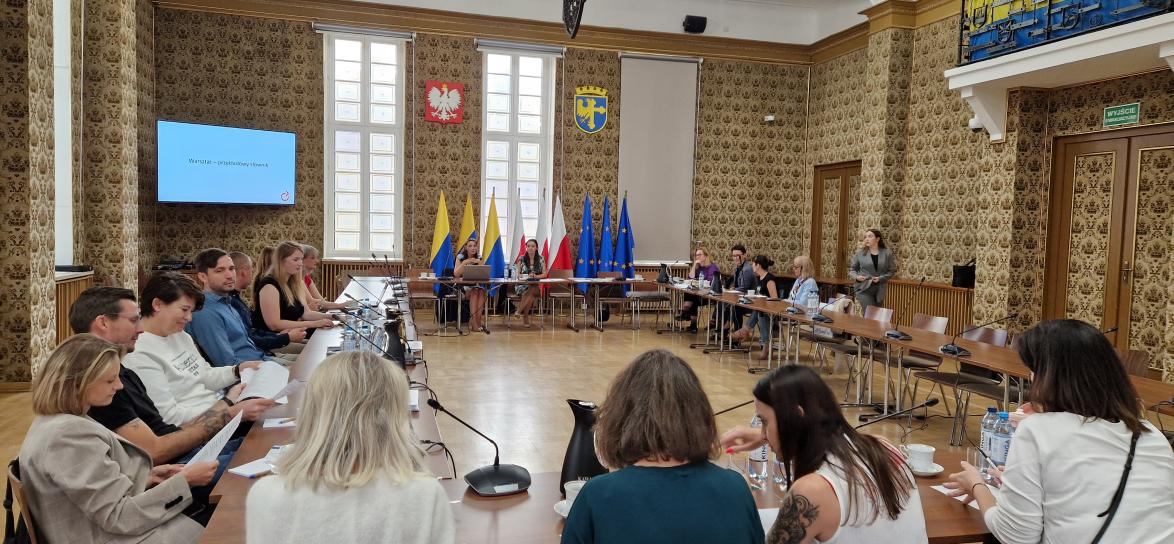 Sala opolskiego ratusza, grupa ludzi siedzących przy stole, część teoretyczna spotkania. 