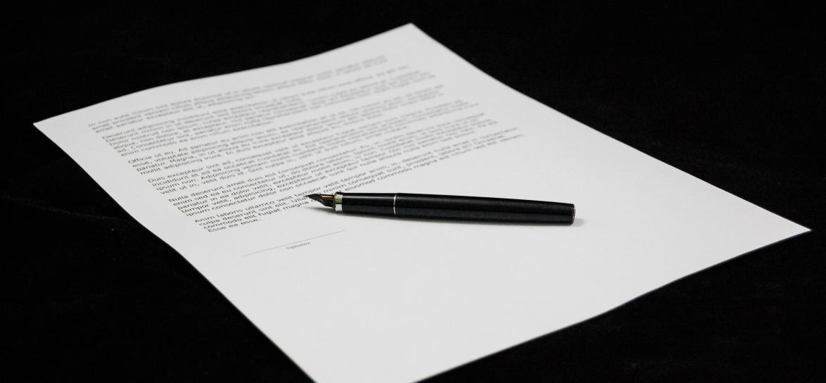 kartka papieru zapisanego do połowy z leżącym na niej piórem