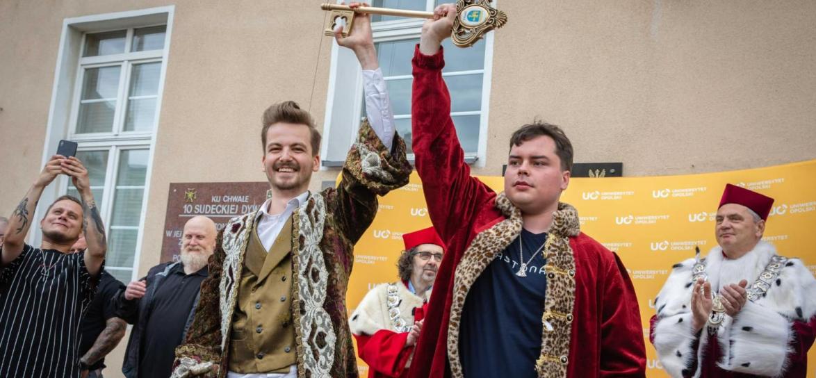 Dwie osoby. Mężczyźni. Studenci. Meżczyzna trzyma klucz z herbem