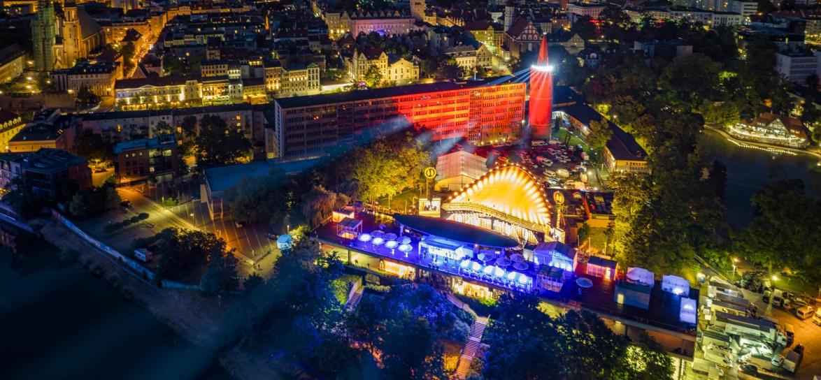 Roświetlony Amfitear podczas Krajowego Festiwalu Polskiej Piosenki w 2023 roku od strony Odry, z widokiem na scene i Wieżę Piastowską