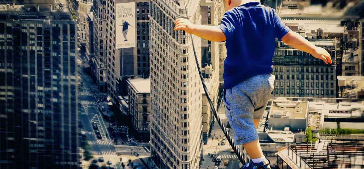 Dziecko idące po linie nad budynkami
