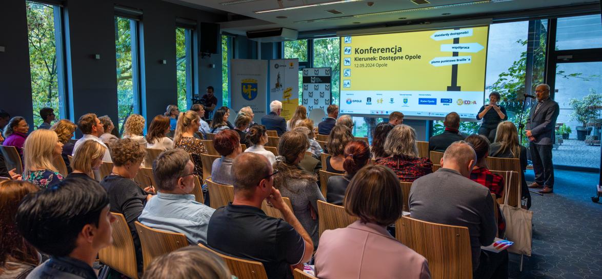 zdjęcie przedstawiające osoby siedzące przed prezentacją podczas konferencji