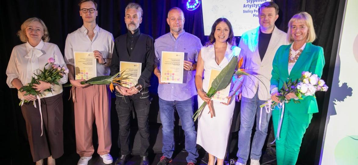 grupa stypendystów stojących w rzędzie z tytułami
