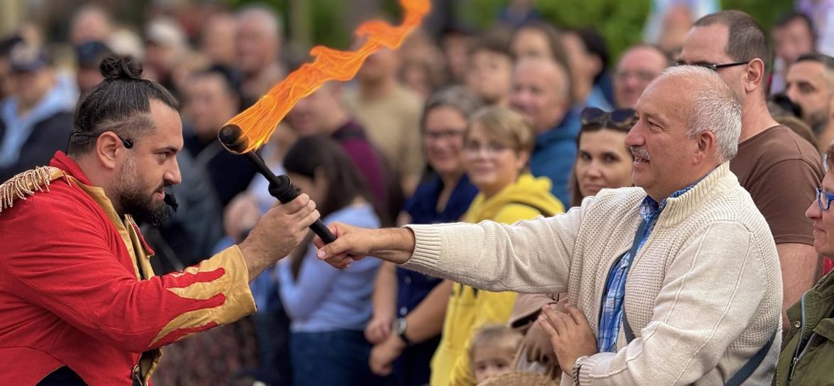 zdjęcie przedstawiające mężczyznę podającego pochodnię innemu mężczyźnie podczas pokazu