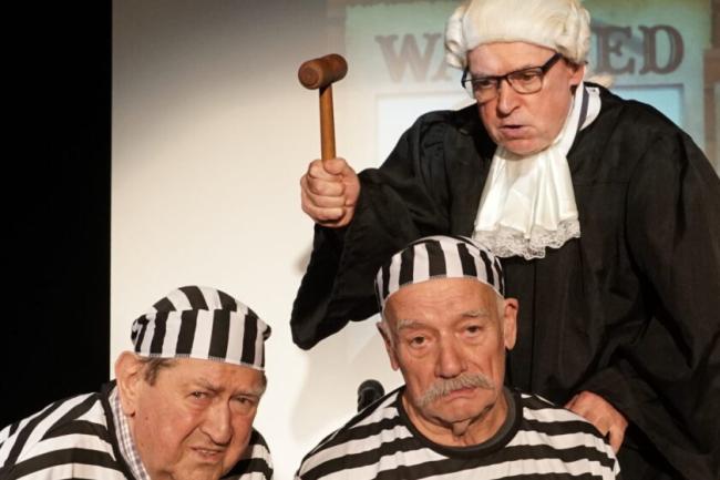 Zdjęcie przedstawia trzy osoby grające w spektaklu. Dwóch gra więźniów, trzeci to sędzia