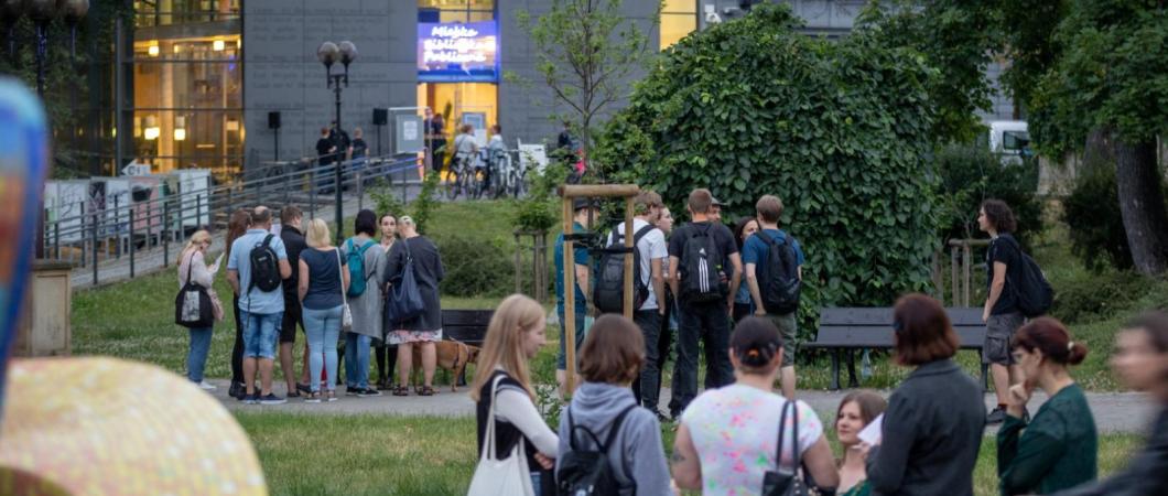 zdjęcie przedstawia budynek Miejskiej Biblioteki Publicznej oraz uczestników stojących przed fontanną, informacje zostały zawarte w tekście
