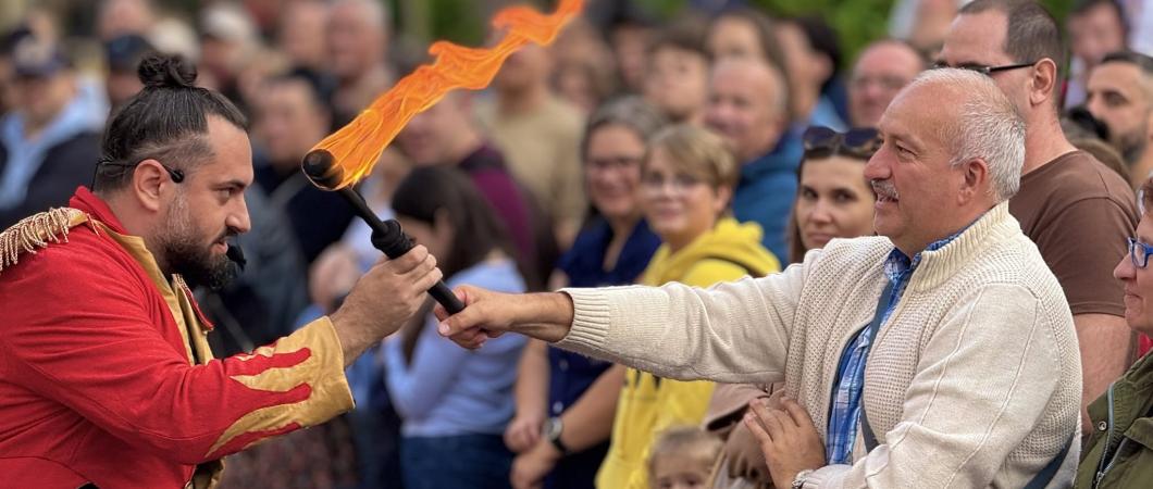 zdjęcie przedstawiające mężczyznę podającego pochodnię innemu mężczyźnie podczas pokazu