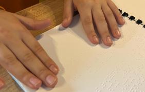 Ręce dziecka dotykające książki napisanej alfabetem Braille'a