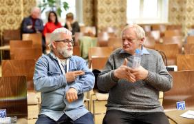 Dwaj starsi panowie rozmawiający ze sobą w języku migowym