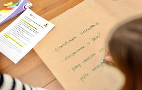 Duży szary arkusz, na którym wypisywane są rozwiązania z zakresu dostępności. Obok karta z pytaniami pomocniczymi