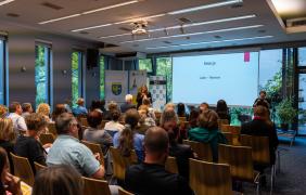 zdjęcie uczestników konferencji, w oddali slajd prezentacji