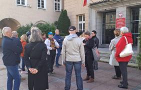 Ludzie stoją przed wejściem do budynku ratusza.