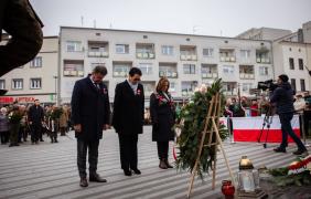 Osoby składające kwiaty pod pomnikiem