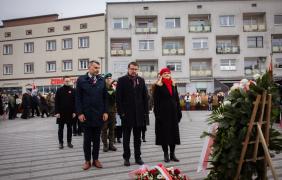 Osoby składające kwiaty pod pomnikiem