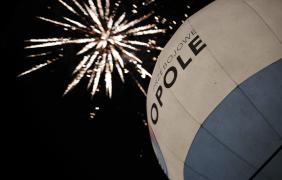 balon z napisem Opole a na niebie fajerwerki w tle