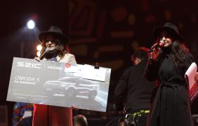 dwie osoby na scenie przedswtawiające voucher do licytacji