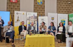 Panel dyskusyjny: grupa sześciu osób siedzi na środku sali